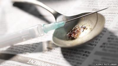 Hypodermic needle and syringe with a pile of heroin on a spoon