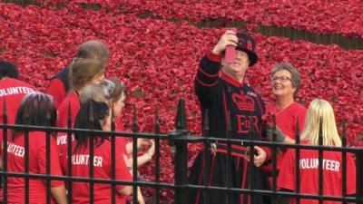 Beefeater taking selfie photograph with volunteer at poppies installation