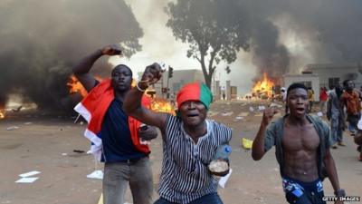 Men in front of burning cars, near the Burkina Faso's Parliament