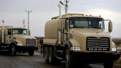 A Peshmerga fighter gestures while driving his fuel truck