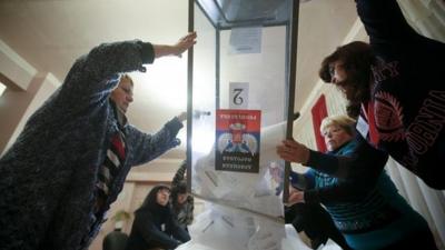 local electoral commission empty a ballot box at a polling station after voting day in Donetsk