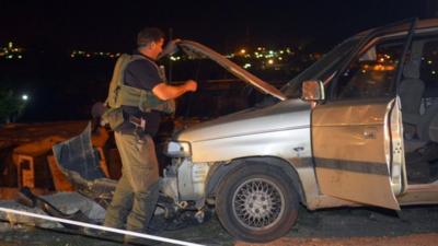 An Israeli soldier inspects a vehicle at the scene of an attack near the West Bank Jewish settlement of Alon Shvut