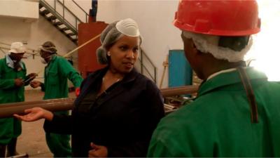 Lorna Rutto speaking to a man in a factory