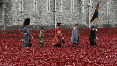 Artist Paul Cummins and servicemen walk past his creation of ceramic poppies at the Tower of London on 11 November 2014