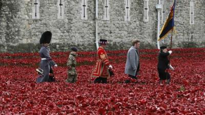 Artist Paul Cummins and servicemen walk past his creation of ceramic poppies at the Tower of London on 11 November 2014