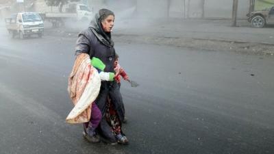 A wounded Syrian woman walks with her children in Aleppo, northern Syria, 15 December 2013