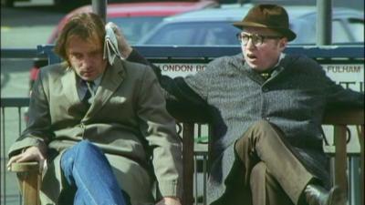 Rik Mayall and Adrian Edmondson sitting outside on the bench in the opening credits of the sitcom 'Bottom'