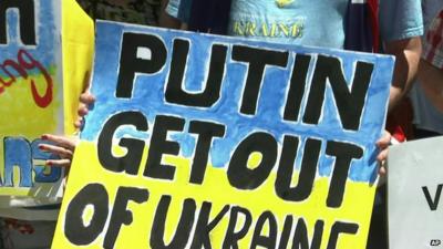 Close up of G20 anti-Putin protester holding banner saying 'Putin Get out of Ukraine'