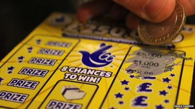 Close up of someone using a two-pound coin on a National Lottery scratchcard