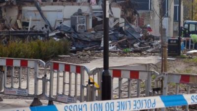 Police tape in front or rubble that was a house