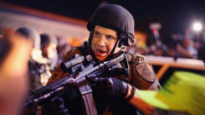 Police officer holds a rifle during August protests in Ferguson, MO