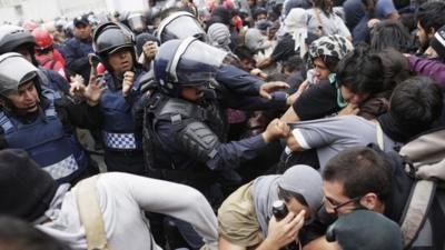 Riot police scuffle with demonstrators during a protest over the 43 missing Ayotzinapa students, near the Benito Juarez International airport in Mexico City November 20, 2014