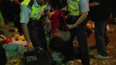 Two police officers remove a protester