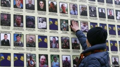 A woman touches a portrait of her husband in Kiev, on a banner with portraits of Ukrainian servicemen killed in the conflict with pro-Russian separatists in eastern Ukraine