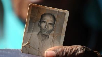 A Bhopal Gas disaster victim holds a frayed photograph of her late husband during a protest rally in Bhopal