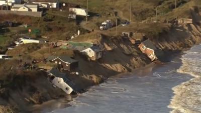 Homes slide into the sea after last year's tidal surge