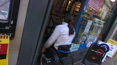 Man in wheelchair entering shop