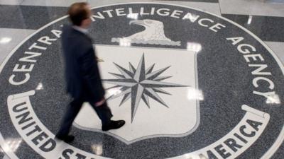 A man walks across a CIA logo