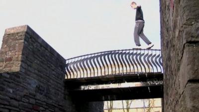 James Rudge walking on the barrier of a bridge