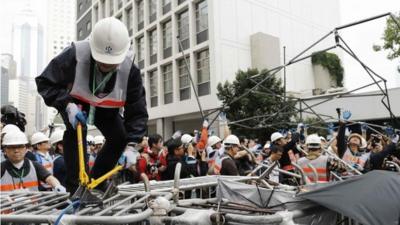 Workers remove a barricade at an area blocked by pro-democracy protesters