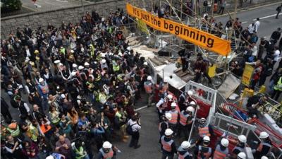 Members of the media and bystanders (L) look on as authorities (C) dismantle a barricade