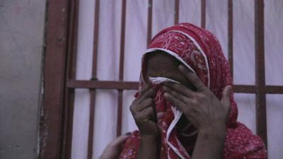 A woman covers her face as she cries