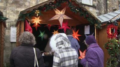 Pensioners shopping at a Winchester Christmas market stall selling decorations in the shape of stars