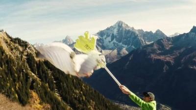 The wingsuit pilot 'high fives' the hand-on-a-stick