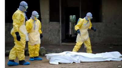 Red Cross workers in Guinea prepare to carry body of ebola victim.