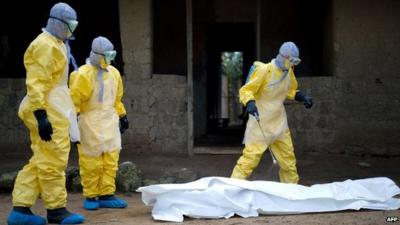 Red Cross workers in Guinea prepare to carry body of ebola victim.