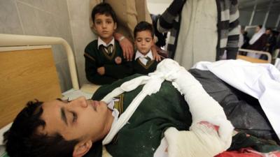 An injured boy with two other children by his bedside