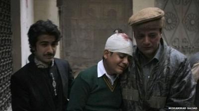 The uncle and cousin of injured student Mohammad Baqair, center, comfort him as he mourns the death of his mother who was a teacher at the school