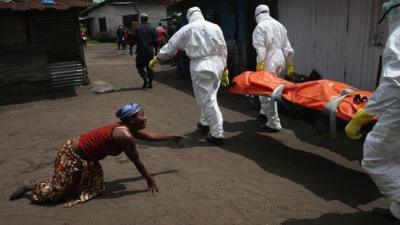 A woman crawls towards the body of her sister as Ebola burial team members take her body for cremation, Monrovia, Liberia