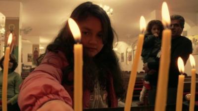 Iraqi Christian child refugee lights a candle in Church