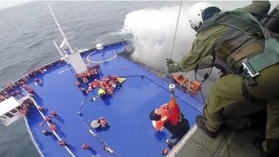 A woman is lifted from the deck of the Italian-flagged ferry