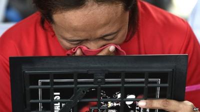 An Indonesian woman breaks down while holding a family picture of passengers onboard the missing plane