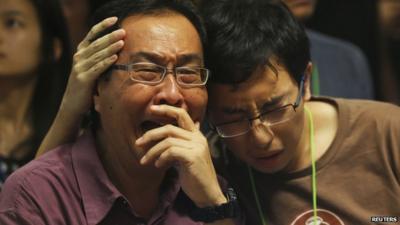 Relatives in Surabya crying as they watch news conference on missing flight QZ8501