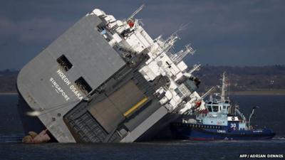 A tug boat alongside the grounded Hoegh Osaka cargo ship in the Solent