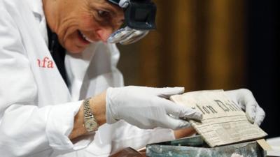 Conservator Pam Hatchfield removes a newspaper from a time capsule