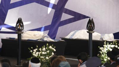 The bodies of two victims are placed on a platform at a cemetery in Jerusalem