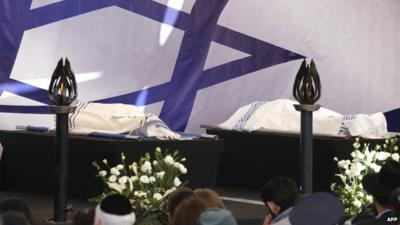 The bodies of two victims are placed on a platform at a cemetery in Jerusalem