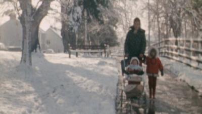 A mother and her two children make their way through the snow in 1971