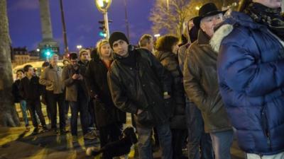 Members of the public queue at a newspaper kiosk in Paris