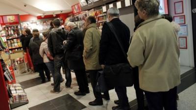 People queue up to buy the new issue of Charlie Hebdo newspaper at a newsstand in Paris