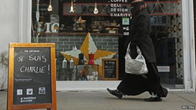 A woman walks past an advertising board on which "Je Suis Charlie!" is written outside a cafe in Brick Lane