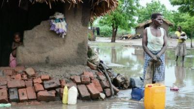 People outside flooded huts