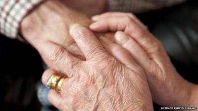 A carer holding an elderly person's hand