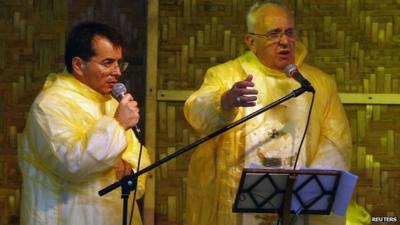 Pope Francis and translator in plastic ponchos