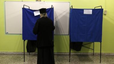 A Greek orthodox priest enters a voting booth