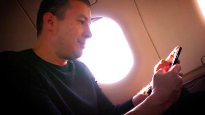 A man using a smartphone on a plane